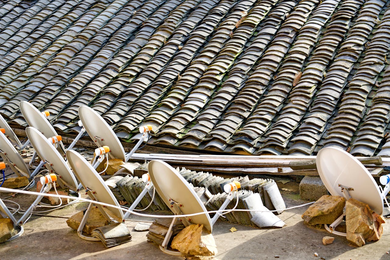 about-img A row of satellite dishes set against an intricately tiled roof, depicting modern technology blending with traditional architecture.
