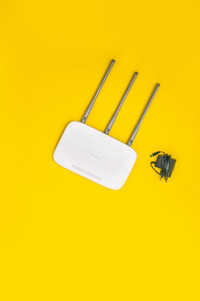 vision White router with three antennas and cables on bold yellow background, ideal for tech concepts.