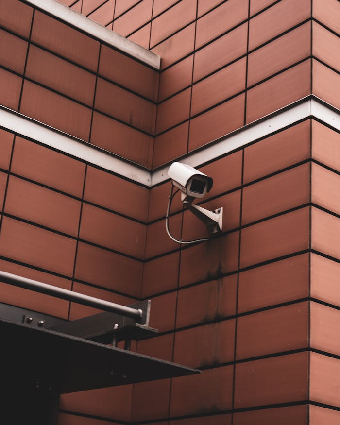 journey-02 Security camera monitoring a red brick building exterior, symbolizing modern surveillance in Germany.